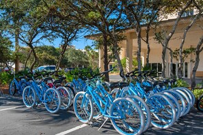 A row of blue bicycles parked in a lot with trees and a building in the background. - Spacious getaway with Gulf view, beach access, tennis & pickleball (Seacrest)