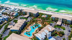 An aerial view of a resort with a swimming pool, beach, and multiple buildings. - Gorgeous condo with lagoon pool, hot tub, beach access & pickleball court! (Seacrest)