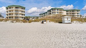 Hotel frente al mar con varios balcones, una torre de salvavidas y playa de arena.
