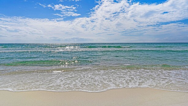 Una playa con agua azul cristalina y una orilla arenosa.