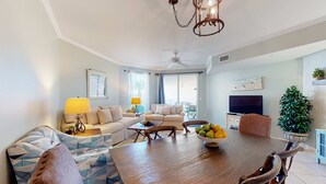 Un salón amplio con una mesa de comedor de madera, sofás y un televisor.