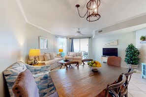 Ein geräumiges Wohnzimmer mit Holzesstisch, Sofas und einem Fernseher.