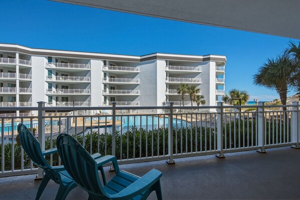 A hotel balcony with a view of a swimming pool and a multi-story building with balconies. - Charming two-bedroom with bunks, balcony overlooking pool & pickleball (Santa Rosa Beach)