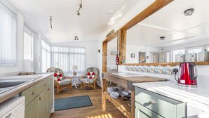 Une cuisine avec des meubles en bois, un grand miroir et une bouilloire rouge.