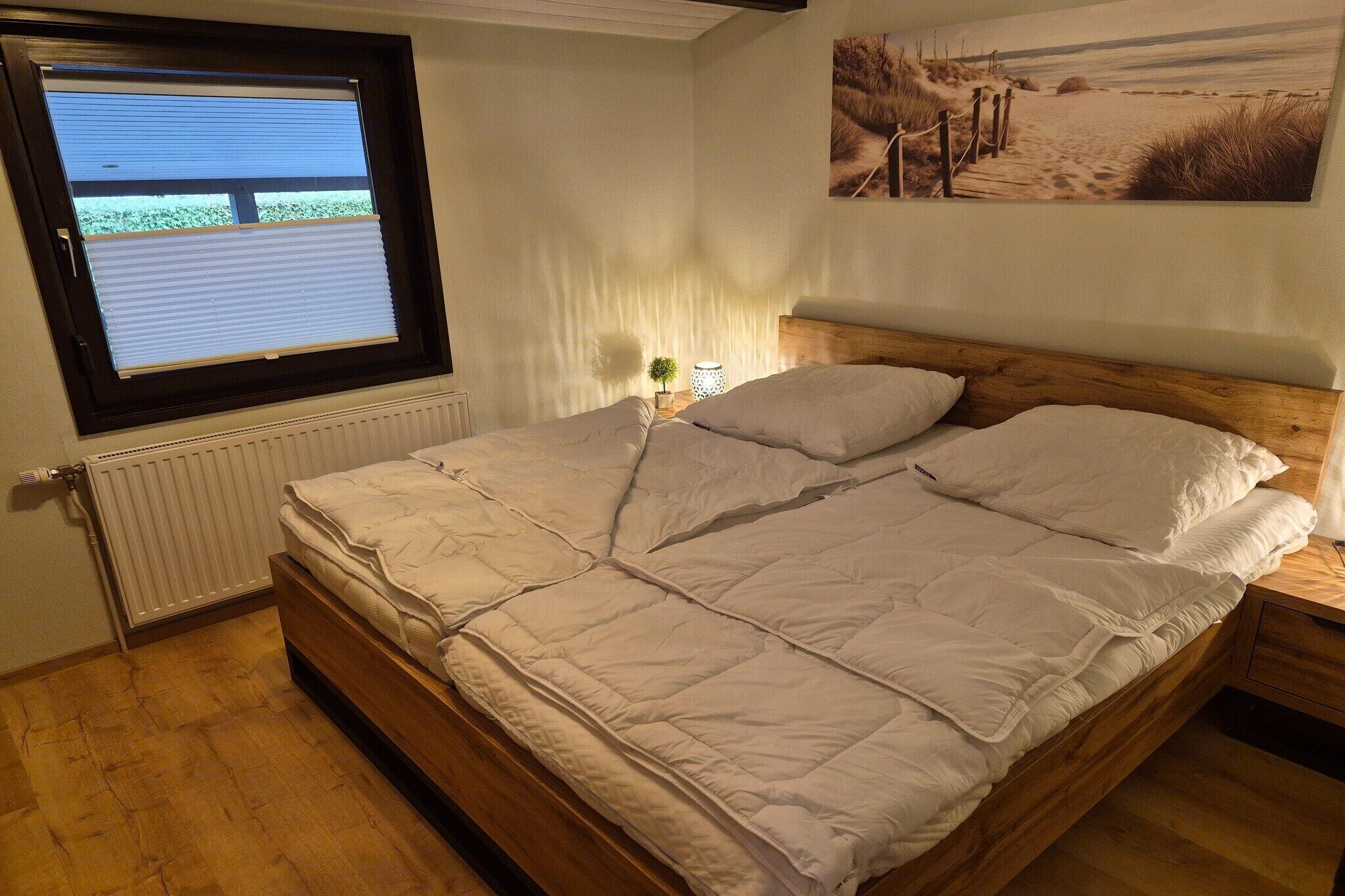 A bedroom with a bed, a window, a radiator, and a painting on the wall.