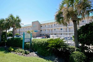 A hotel with a sign reading "Crystal Sands Resort & Spa" surrounded by lush greenery and palm trees. - Oceanfront Condo with AC, WiFi, Shared Pool, & Seasonal Beach Service Rentals (Destin)