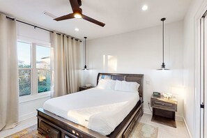 A bedroom with a large bed, a ceiling fan, bedside lamps, and a nightstand with a lamp. - Home near beach and 30A with balcony, yard, patio, grill, Washer & Dryer (Santa Rosa Beach)