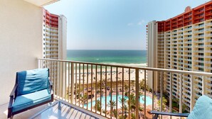 A balcony with a view of the beach and a pool area. - Updated oceanfront condo with pools, hot tub, W/D, AC, & views (Panama City Beach)