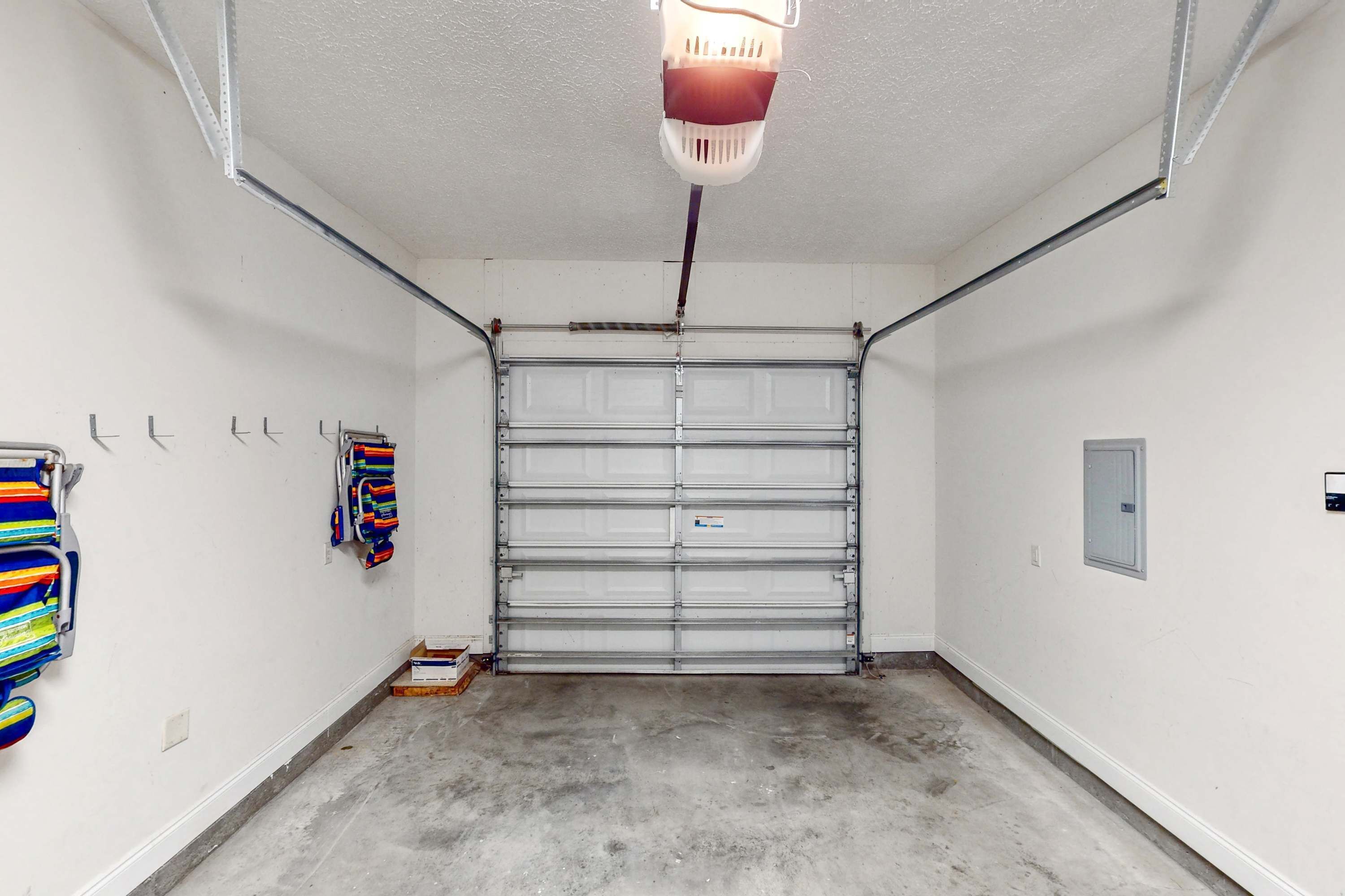 Un garage con porta metallica chiusa, pavimento in cemento e una lampada a soffitto.