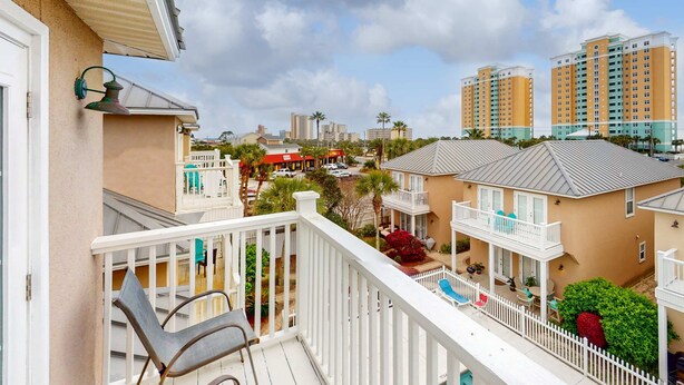 A balcony with a white railing, a chair, and a small table. - Ideal Coastal Retreat w/ Shared Pool, Private Balcony, & Beach Access Nearby (Panama City Beach)