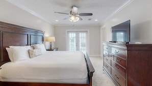 A bedroom with a large bed, a dresser, a ceiling fan, and a television. - Ideal Coastal Retreat w/ Shared Pool, Private Balcony, & Beach Access Nearby (Panama City Beach)