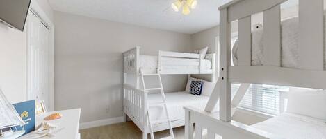 A child's bedroom with bunk beds, a desk, and a ceiling fan.
