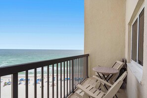 A balcony with a view of the beach, a table, and chairs. - Gorgeous beachfront condo, shared pool and beach access (Panama City Beach)