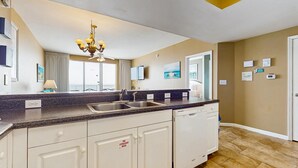 A modern kitchen with a granite countertop, white cabinetry, and a built-in dishwasher. - Majestic Sun B1011 | Beachfront Condo with Pool! (Miramar Beach)