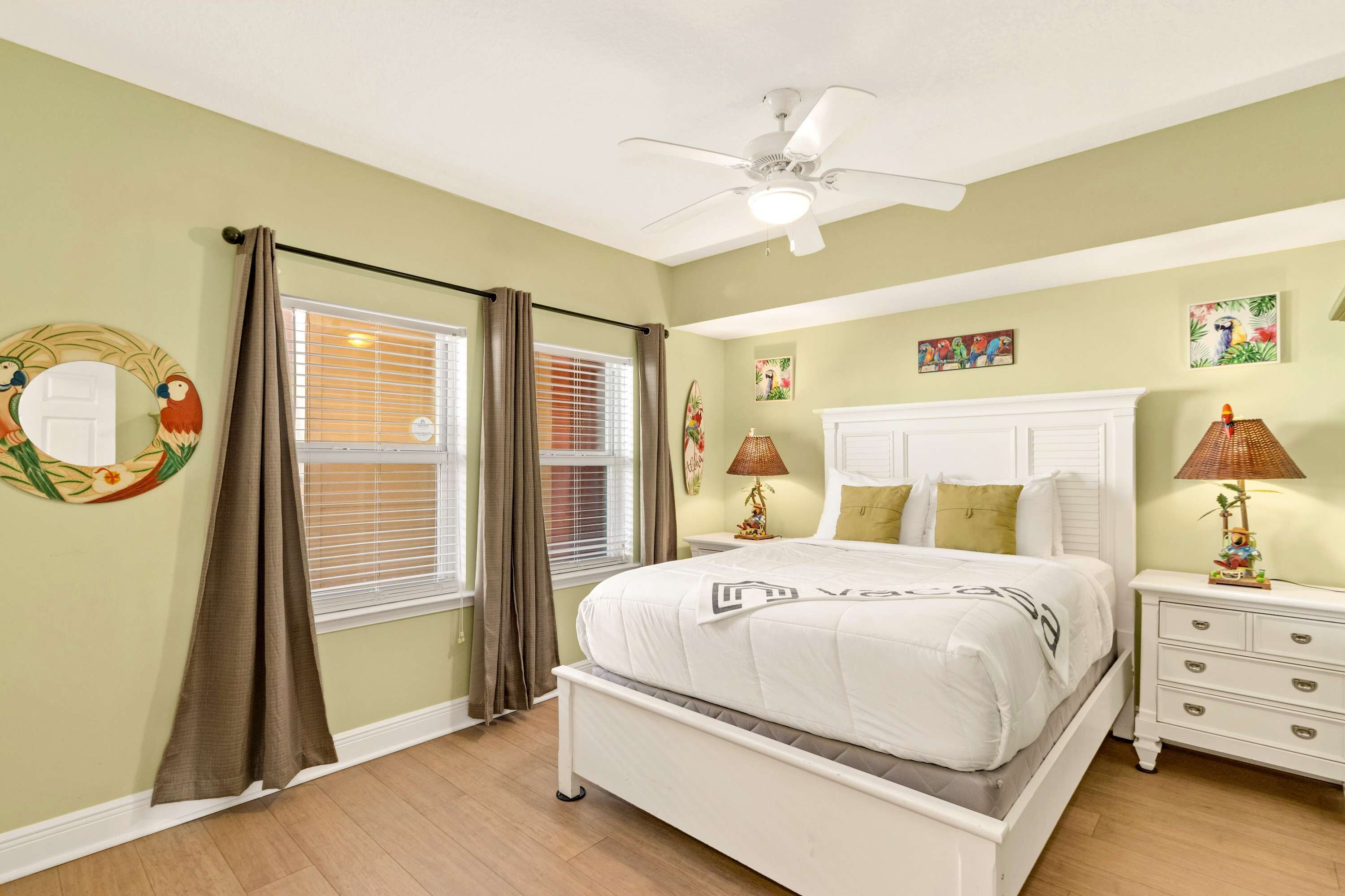 A bedroom with a bed, nightstands, a ceiling fan, and a window with curtains.
