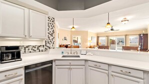 A kitchen with white cabinets, a built-in dishwasher, and a coffee maker.