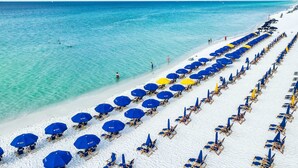 Een strand met rijen blauwe en gele parasols en strandstoelen.