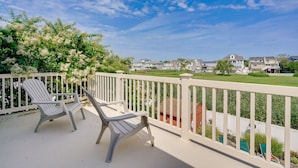 Un balcone con due poltrone Adirondack, un parapetto bianco e vista su case sullo sfondo.