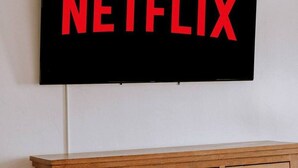 Un téléviseur à écran plat fixé au mur, avec le mot « NETFLIX » affiché en lettres rouges.