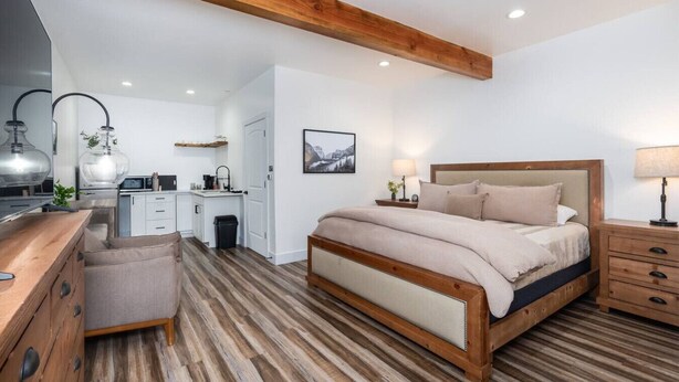 Une chambre moderne avec un lit en bois, un bureau et un coin cuisine.