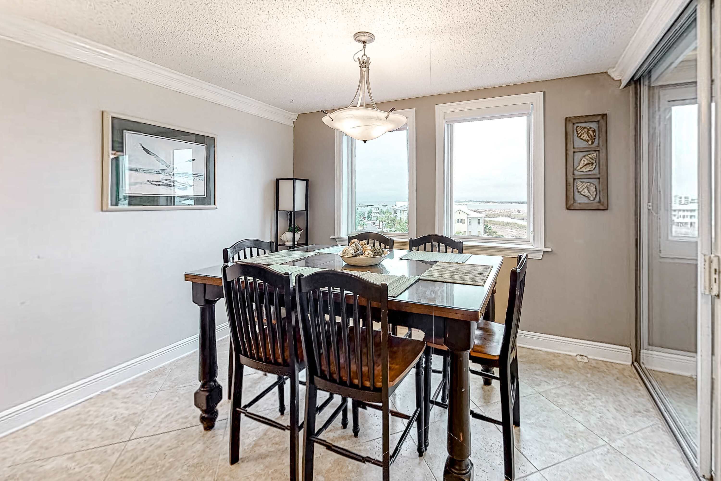 A dining room with a large table, six chairs, and a chandelier.