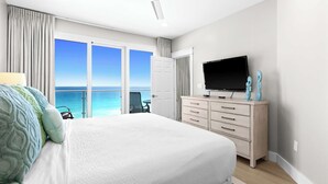 Ein Schlafzimmer mit einem großen Bett, einem Fernseher, einem Schreibtisch und Meerblick.