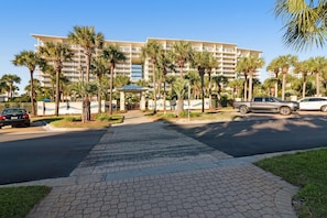 A hotel with a central courtyard, palm trees, and a paved walkway. - Gorgeous beachfront penthouse getaway with shared pool and private balcony (Destin)
