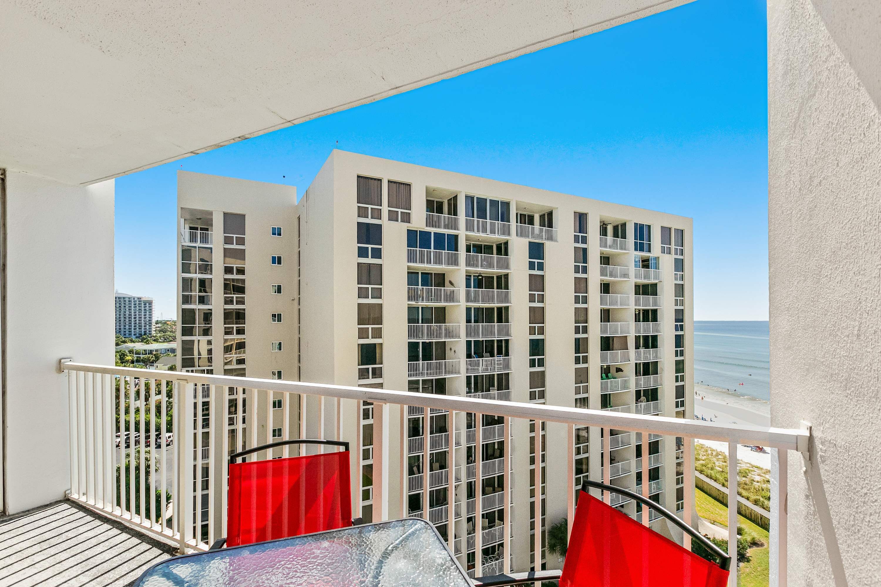 A balcony with a view of a multi-story building and a beach.