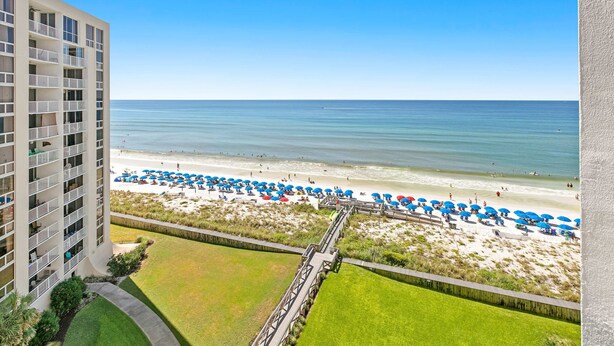 Ein Hochhaus-Hotel mit Blick auf einen Strand, eine Promenade und Strandsonnenschirme.