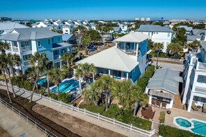 Un área residencial costera con varias casas de dos pisos, una piscina y vista al océano.