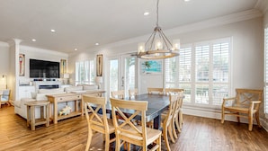 A spacious kitchen with a dining area, wooden flooring, and large windows. - Happy Hours (Destin)