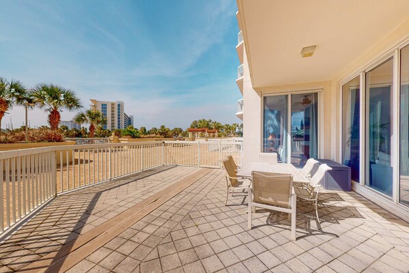 A balcony with a tiled floor, white railing, and outdoor furniture including chairs and a table. - Garden-view condo with lagoon & kid's pools, beach access, on-site eateries & AC (Destin)