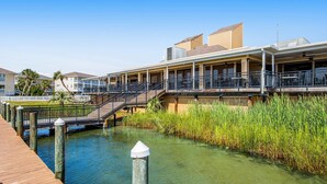 A waterfront hotel with a wooden deck, a bridge, and a grassy area. - Sparkling Studio with Shared Pools, Hot Tubs, Golf, Tennis, & a Private Beach (Destin)