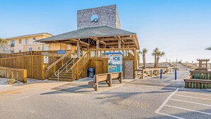 A beachside building with a wooden structure, a staircase, and a sign for 'Baggard Ice'. - Sparkling Studio with Shared Pools, Hot Tubs, Golf, Tennis, & a Private Beach (Destin)
