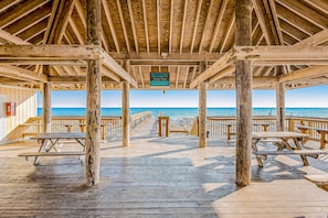 A wooden deck with picnic tables and a sign indicating beach access. - Sandpiper Cove Villa 20 (Destin)