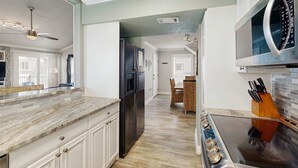 A kitchen with white cabinets, a black refrigerator, a microwave, and a stove. - Sandpiper Cove Villa 20 (Destin)