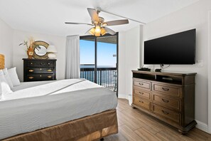 A hotel room with a bed, a dresser, a television, and a balcony with a view. - 10th Floor Beautiful Condo, Splash pad w multiple pools & hot tub (Destin)