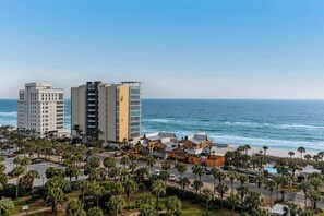 Ein Küstenhotel mit mehreren Gebäuden, einem Strand und Palmen.