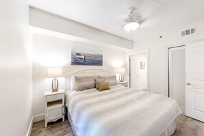 Ein Schlafzimmer mit Bett, Nachttischen, Deckenventilator und einer Tür.