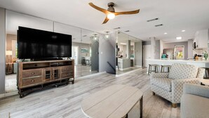 Ein modernes Wohnzimmer mit Flachbildfernseher, Holzunterhaltungseinheit und Deckenventilator.
