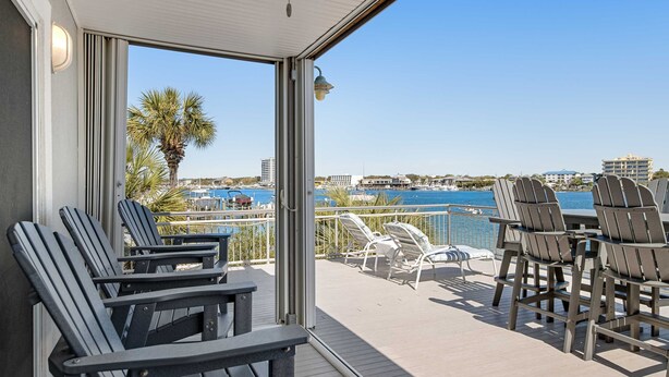 Ein Balkon mit Adirondack-Stühlen, einem Tisch und Blick auf den Yachthafen und die Gebäude.