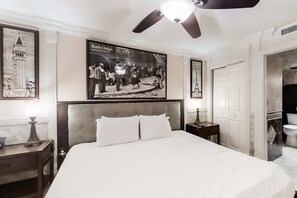 A hotel room with a large bed, a ceiling fan, framed pictures on the walls, and a view into the bathroom. - Beachfront, 15th-floor condo with great Gulf view, hot tub, pools & gyms (Destin)