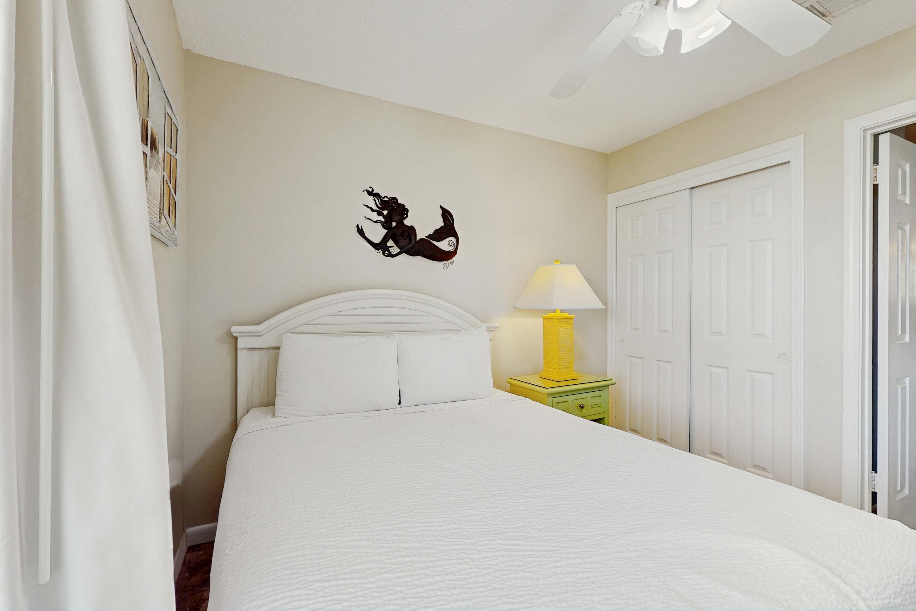A bedroom with a bed, a wall-mounted decoration, a bedside lamp, and a door.