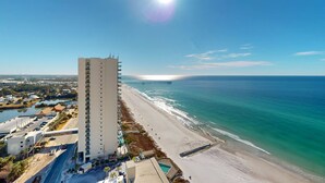 Ein Hochhaus-Hotel mit Blick auf einen Strand und einen in der Ferne liegenden Steg.