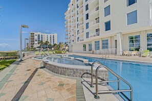 A swimming pool area with a stone-tiled deck, a lounge chair, and a small pool. - Welcoming, 4th-floor condo on the beach with pool, hot tub & balcony (Perdido Key)