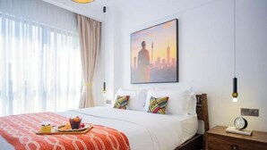A hotel room with a bed, a breakfast tray, a nightstand, a wall clock, and a cityscape painting. - Modern JW 1BR Westlands Nairobi homes with pool and gym (Nairobi)