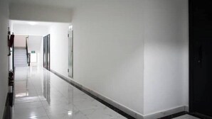 A hallway with a shiny tiled floor, white walls, and a black door at the end. - Modern JW 1BR Westlands Nairobi homes with pool and gym (Nairobi)