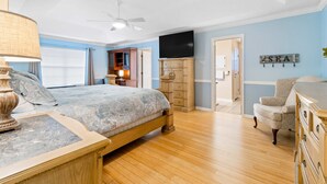 Ein Schlafzimmer mit Bett, einem Holzschrank, Fernseher und Deckenventilator.