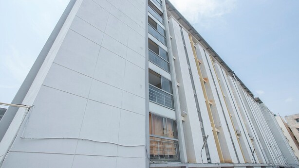 A modern building with a white facade, multiple windows, and a vertical structural design.
