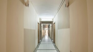 A long, narrow hallway with a tiled floor and doors on both sides.